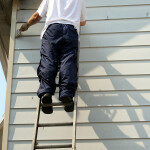 man painting house on ladder in the sun light.